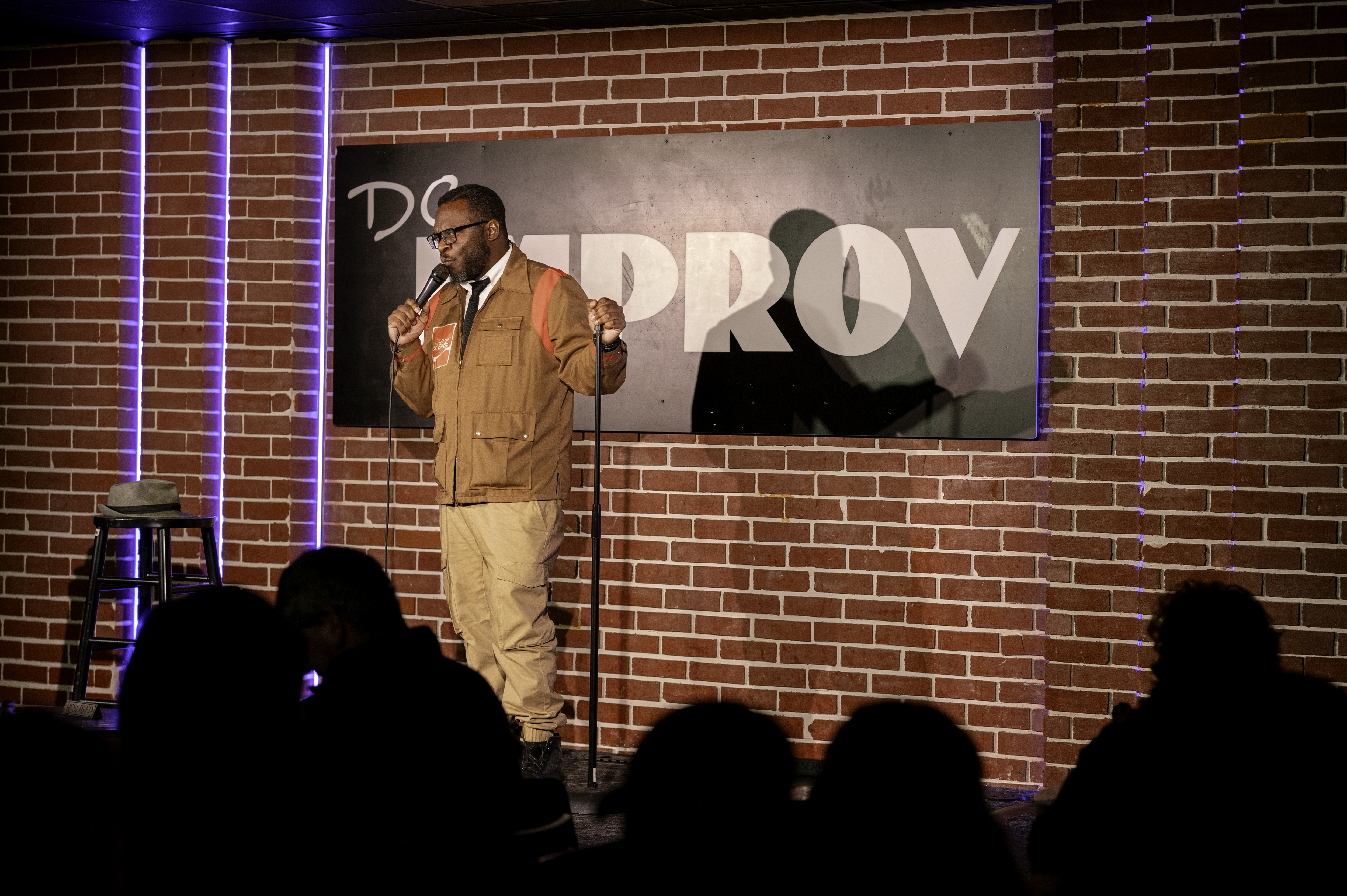 Earl Wyatt II on the DC Improv stage in a tan jacket